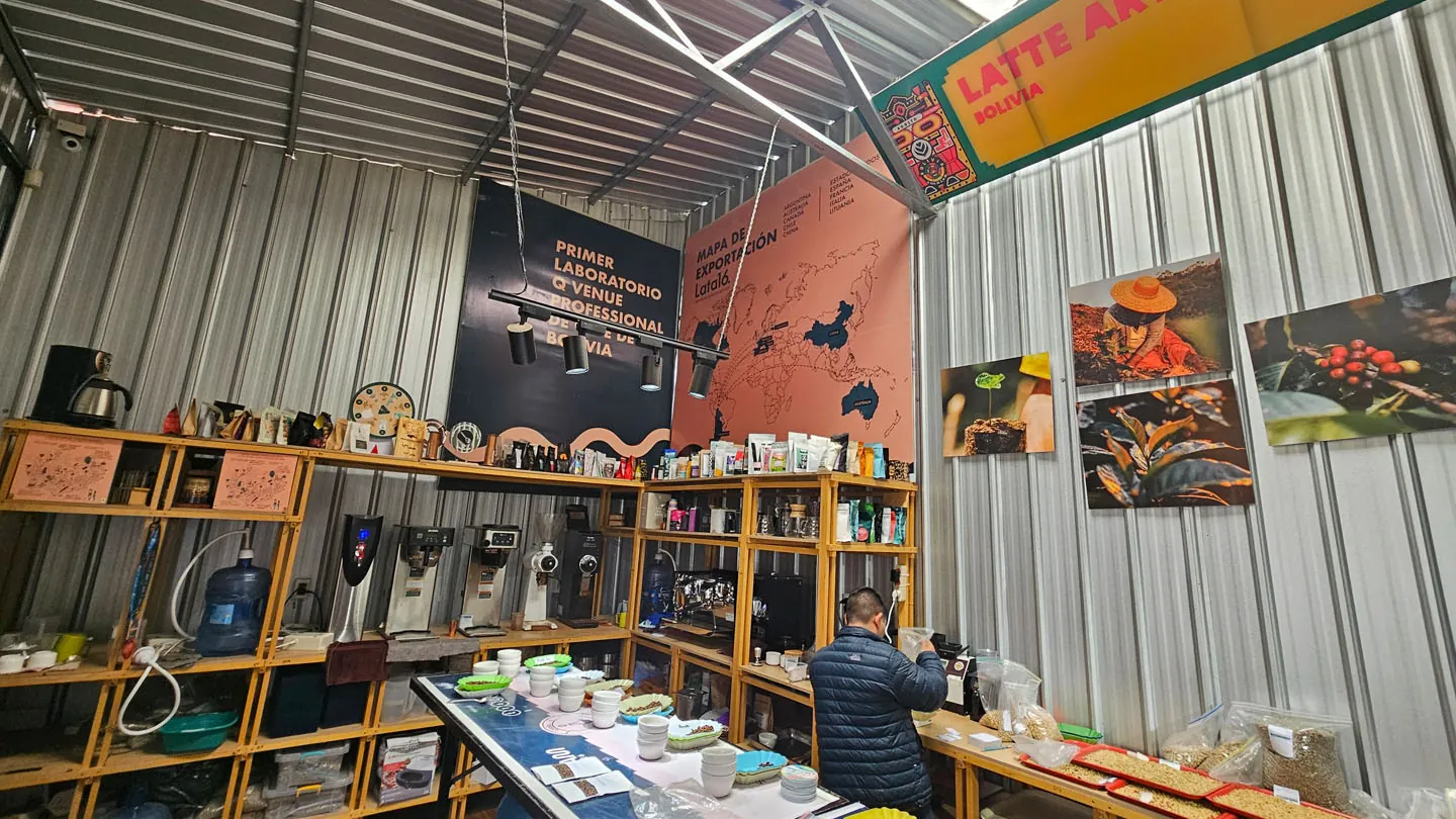 Inside the cupping laboratory of a coffee plant in Caranavi, Bolivia, with a cupping table, grinders and wooden shelving.